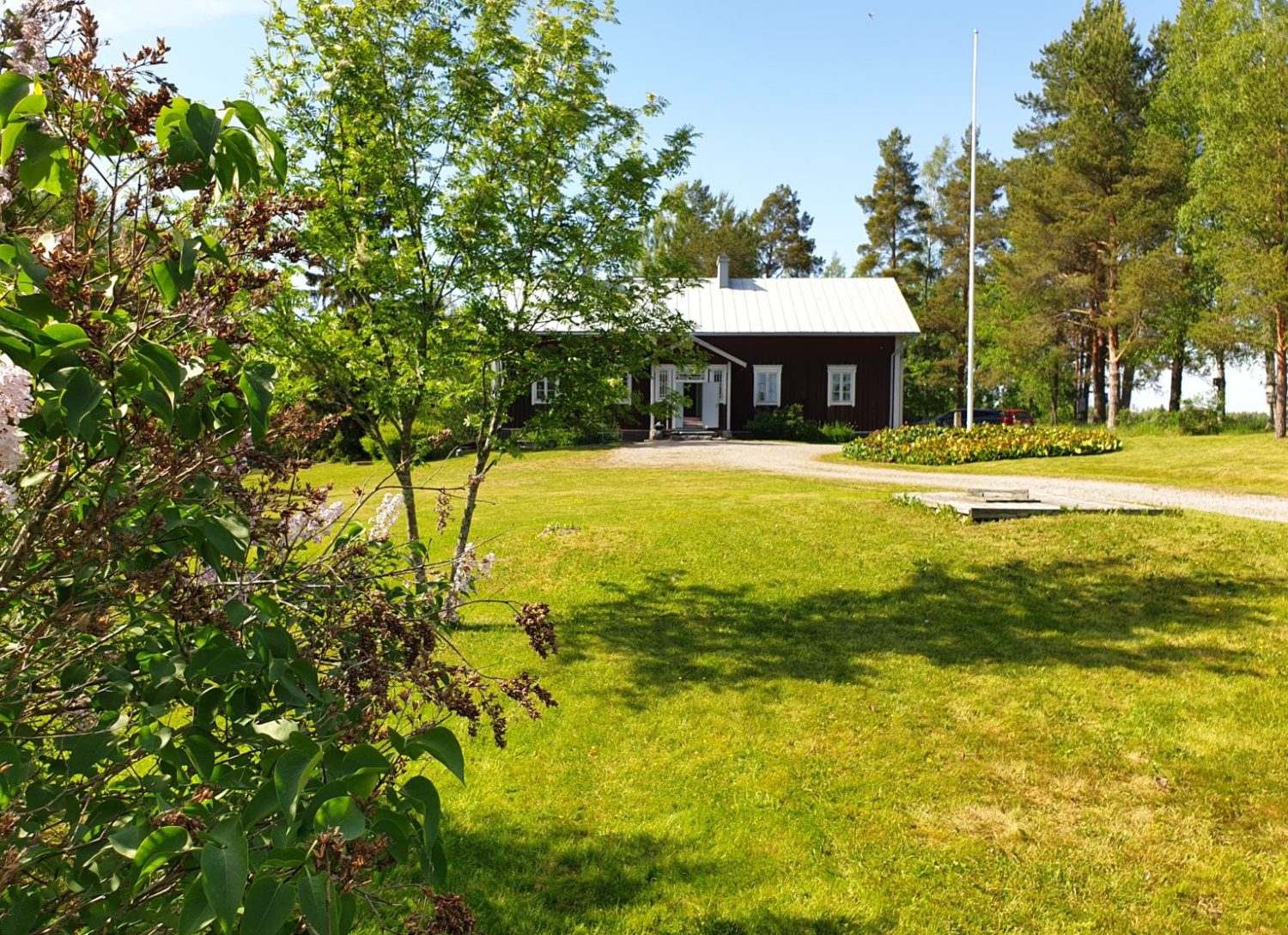 punainen vanha kotiseututalo ja kesäinen pihapiiri